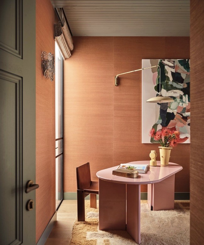 Abstract artwork on a terracotta grasscloth wall in a study with a pink desk, The Style Workshop
