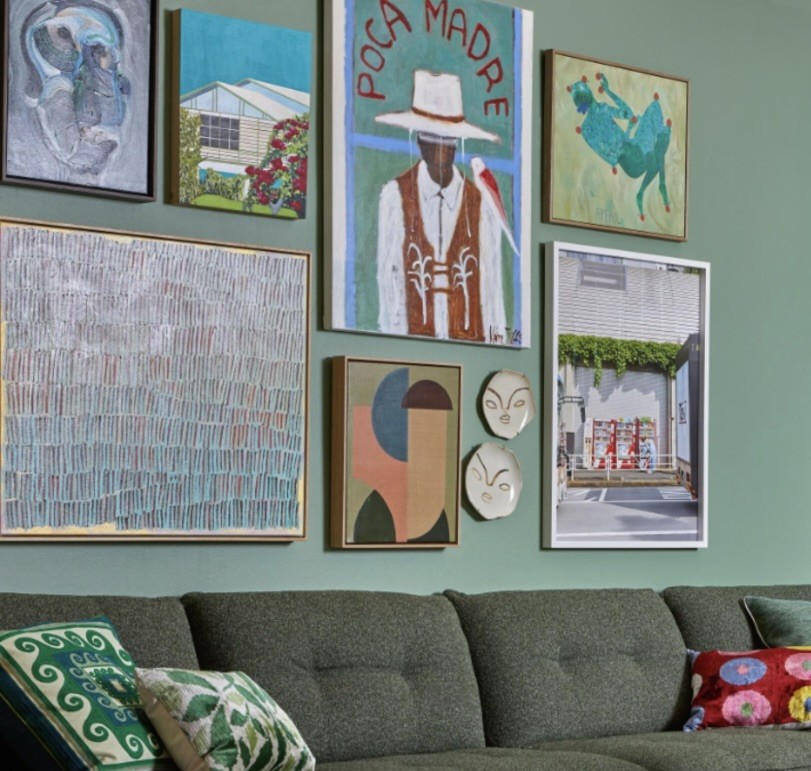 Colourful gallery wall of contemporary works above a green sofa, The Style Workshop
