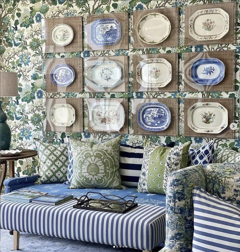 Blue and white plates arranged in a grid on patterned wallpaper above a daybed, The Style Workshop