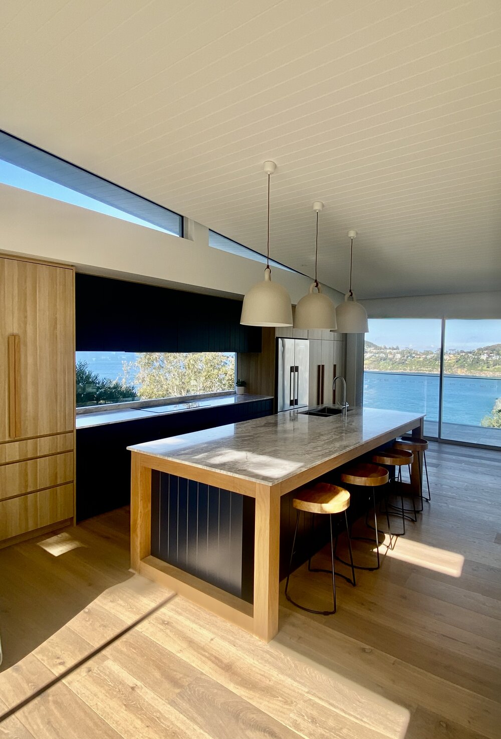 Whale Beach House kitchen with navy joinery and direct water views, The Style Workshop