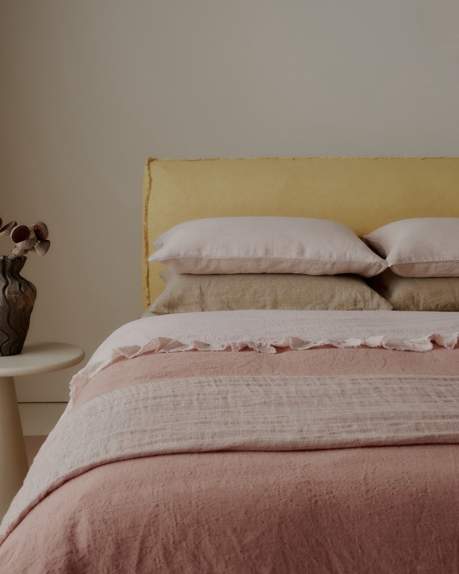 Bed styled with soft pink and warm yellow linen bedding, The Style Workshop