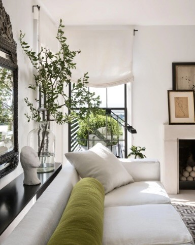 Living room with sheer curtain, branch of greenery in a glass vase and white sofa, The Style Workshop