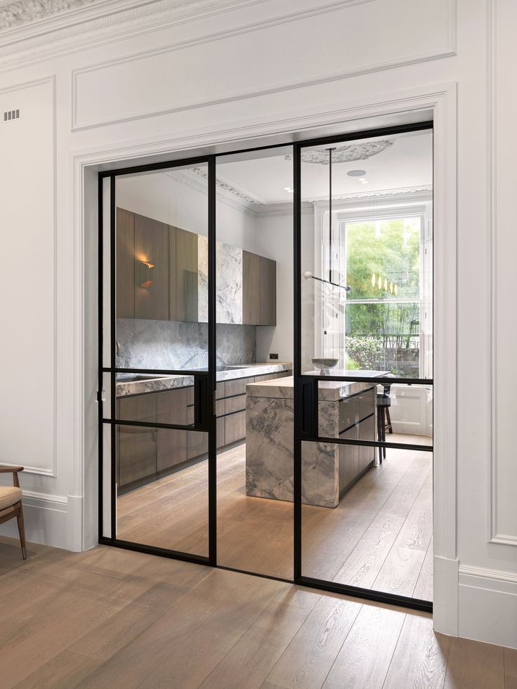 Steel-framed glazed sliding doors opening between rooms, filling the space with natural light