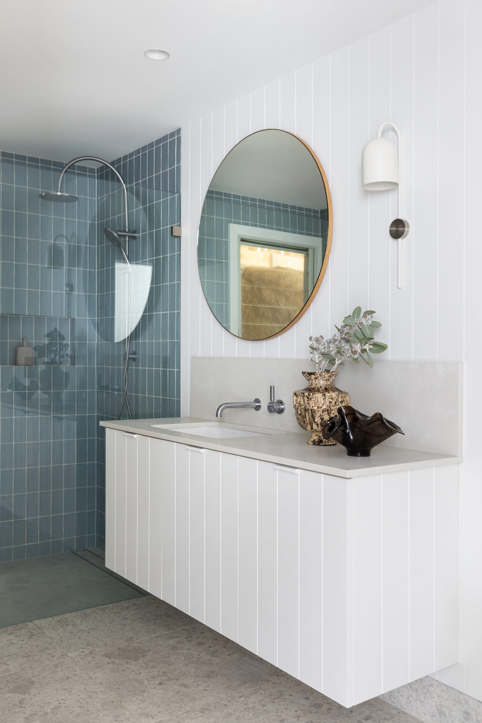 Finished bathroom at the Whale Beach project with blue tiled shower and round mirror