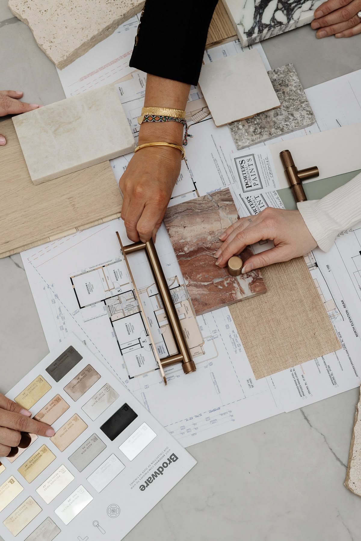 Two people reviewing hardware and material samples against a floor plan