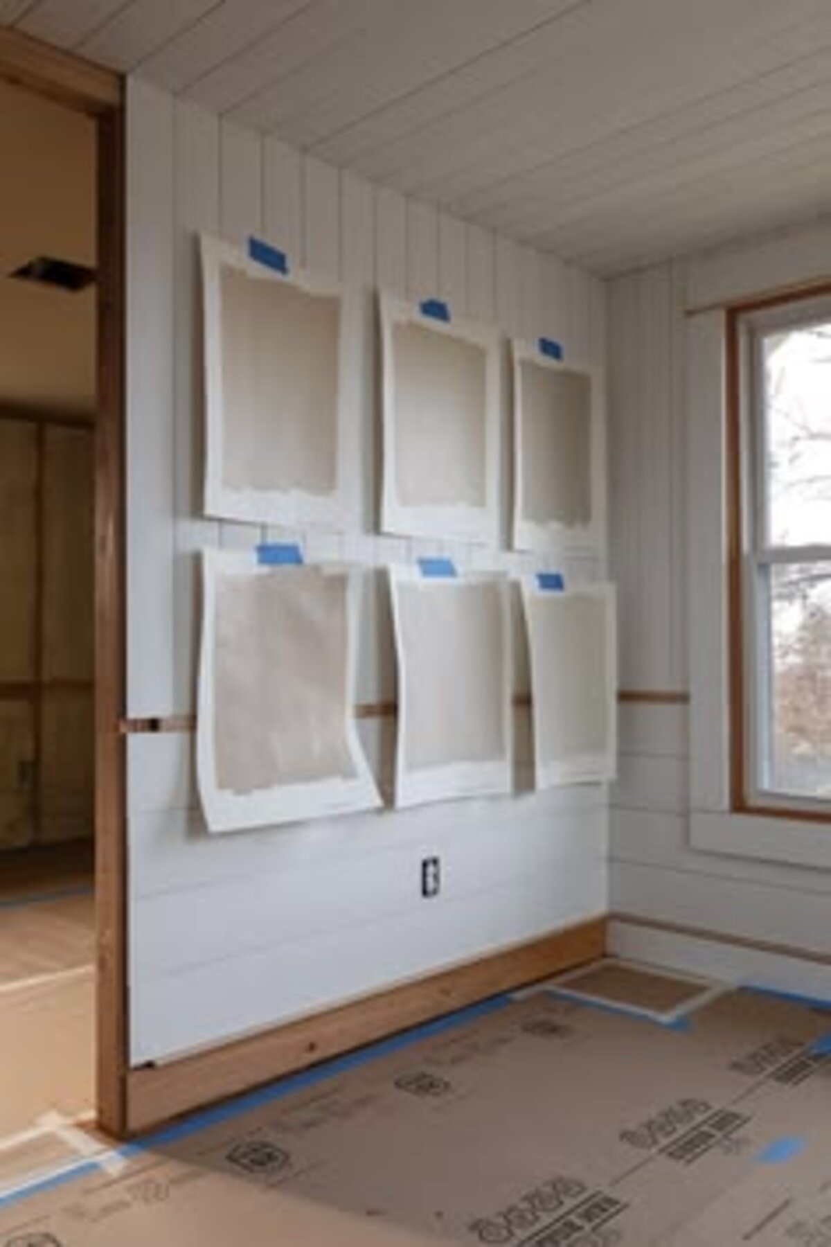 Paint drop samples taped to a shiplap wall during a site visit