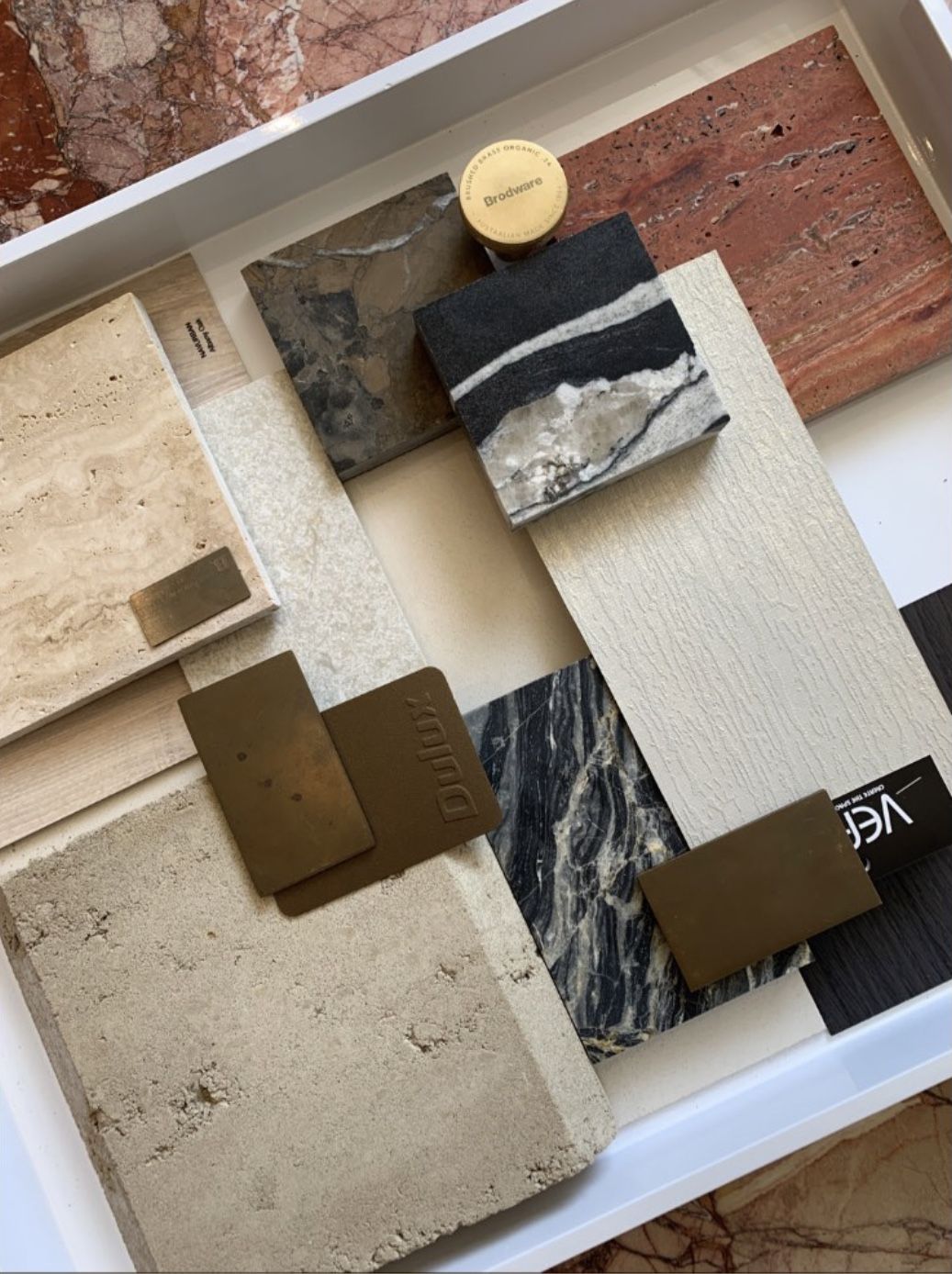 Presentation-ready material palette with marble, travertine, timber and brass finishes, The Style Workshop