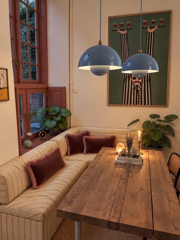 Two blue dome pendants hung low over a timber dining table with a banquette