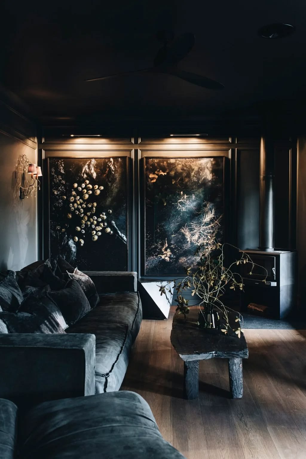 Dark living room in the evening with wall lights and picture lights over large artworks