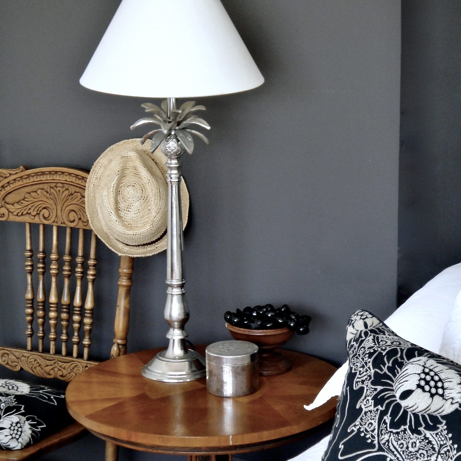 Carved vintage chair and round timber side table against a charcoal wall, The Style Workshop