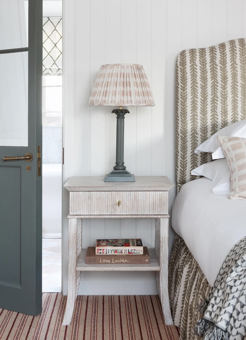 Bedroom nook with leaf-print striped headboard and patterned lampshade
