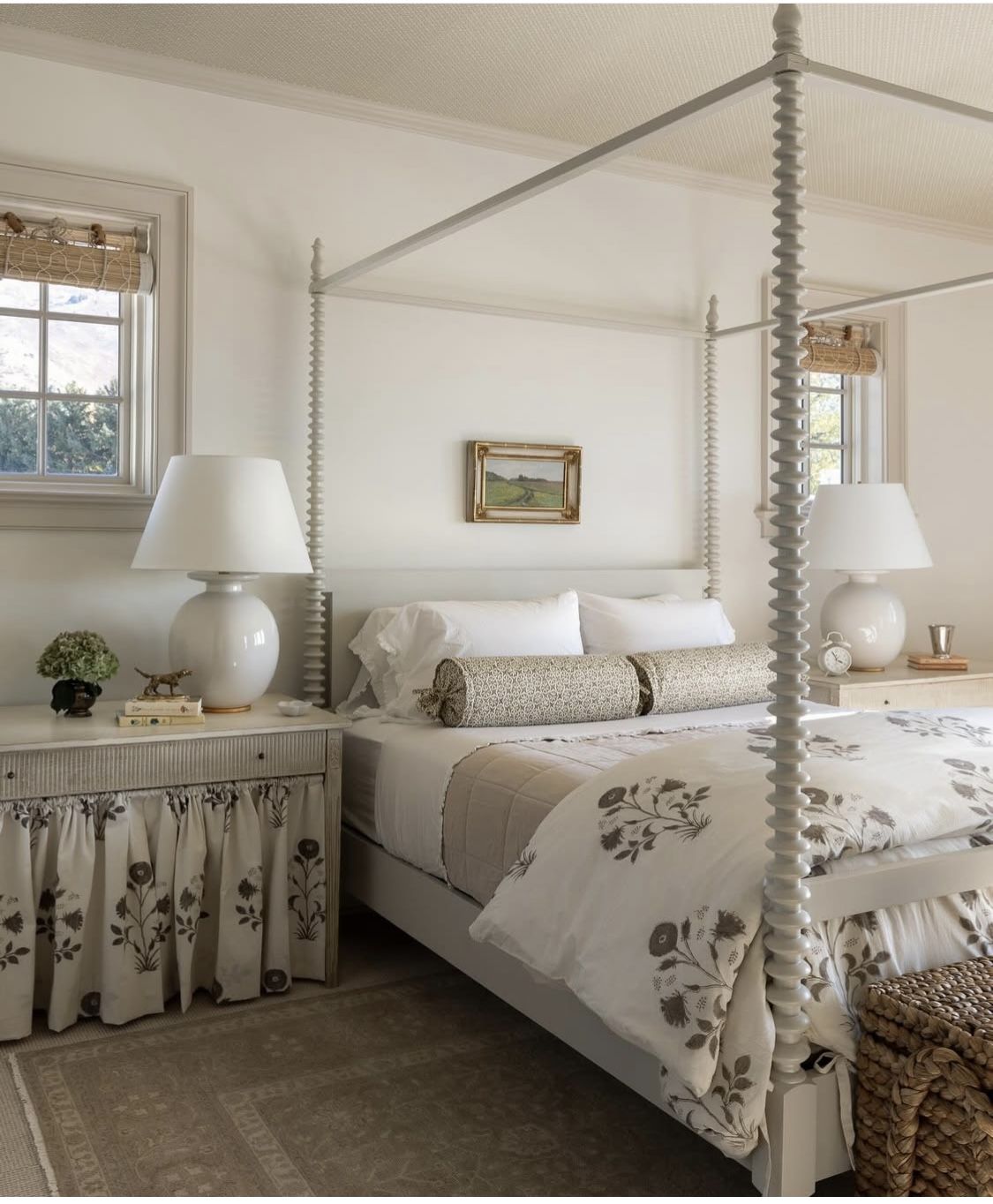 Canopy bed dressed in soft floral linen with plain ceramic lamps