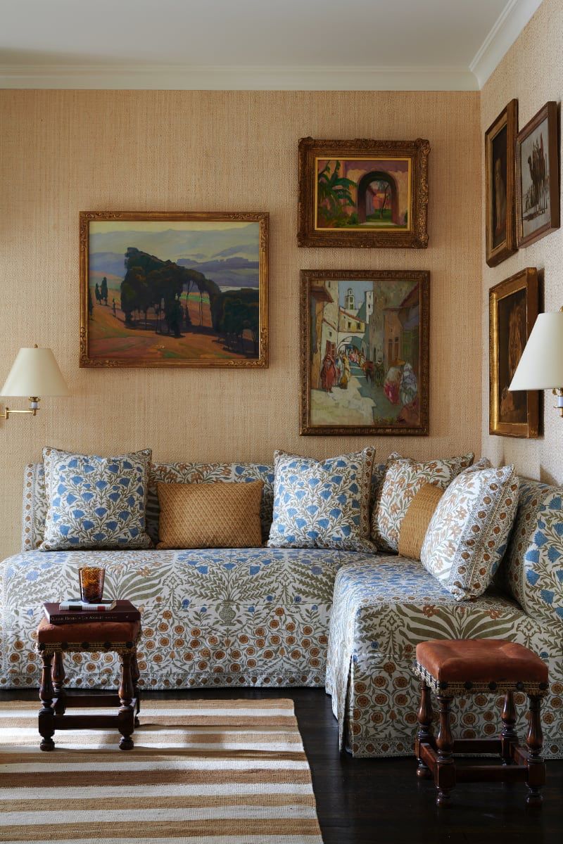 Floral upholstered sofa beneath a gallery wall of framed landscape paintings