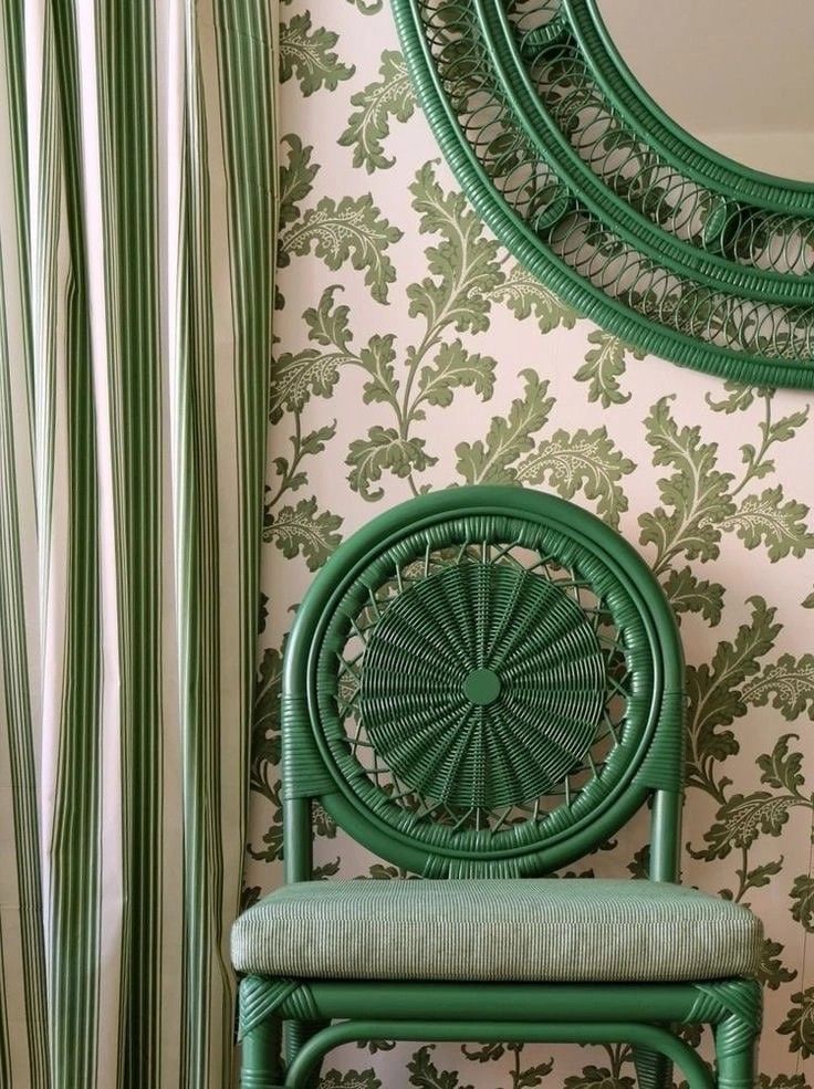 Green leaf print wallpaper with a striped curtain and green rattan chair