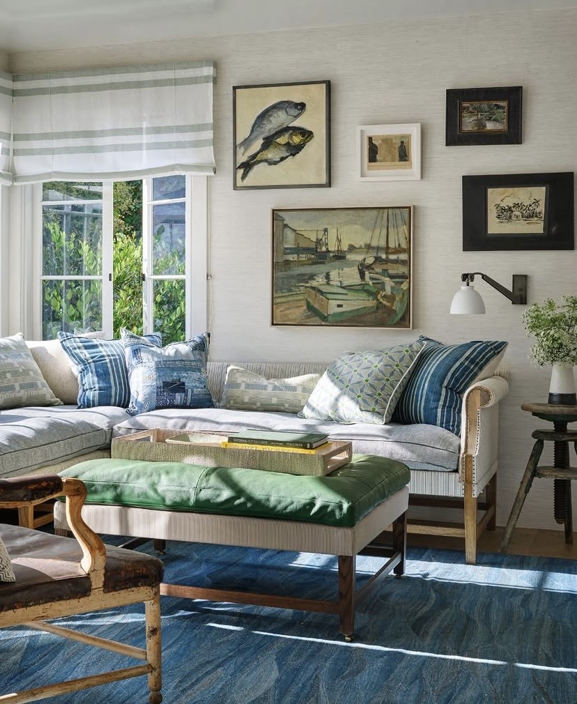 Neutral linen sofa beneath a gallery wall of coastal and fish artwork