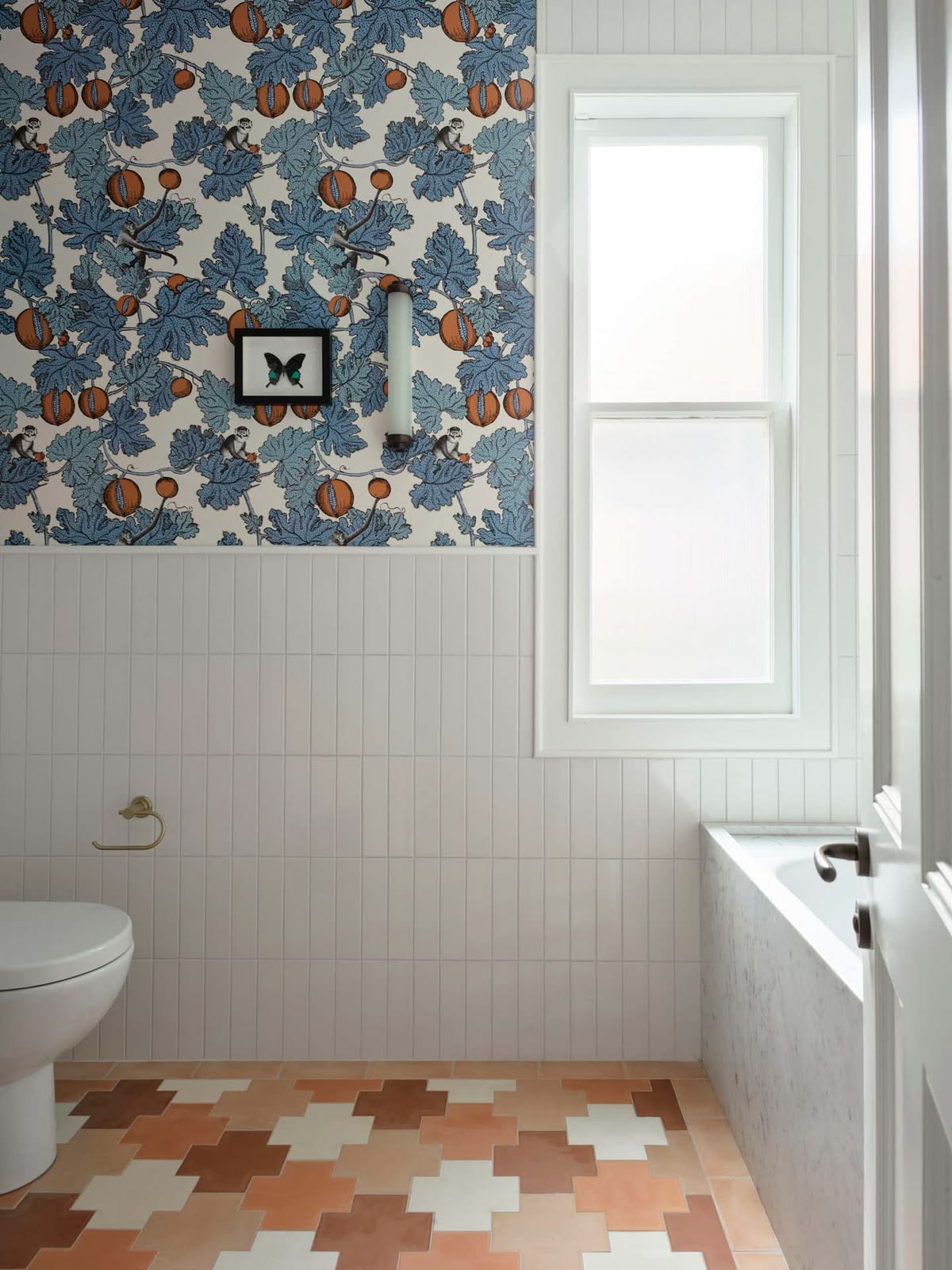 Bathroom with hand-blocked wallpaper and patchwork terracotta tile floor