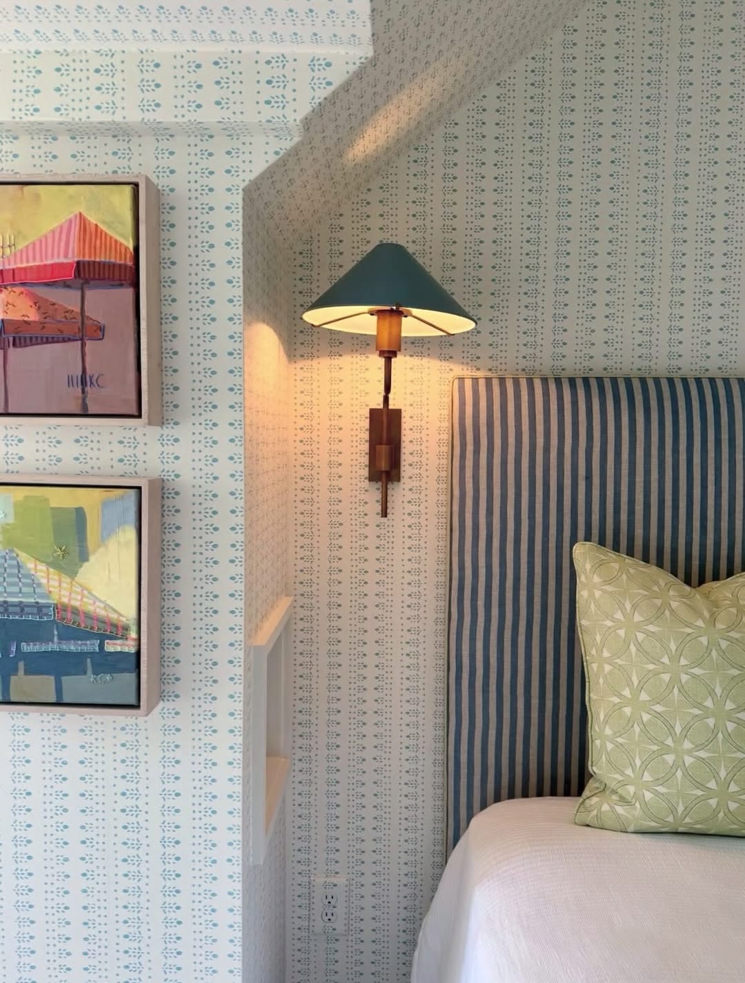 Striped headboard with patterned wallpaper and framed artwork