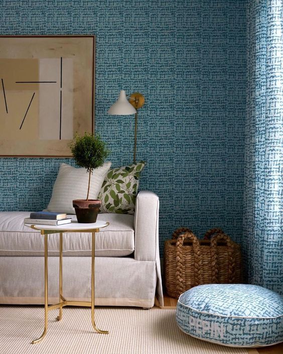 Living room with tonal blue textured wallpaper, matching curtains and a plain linen sofa