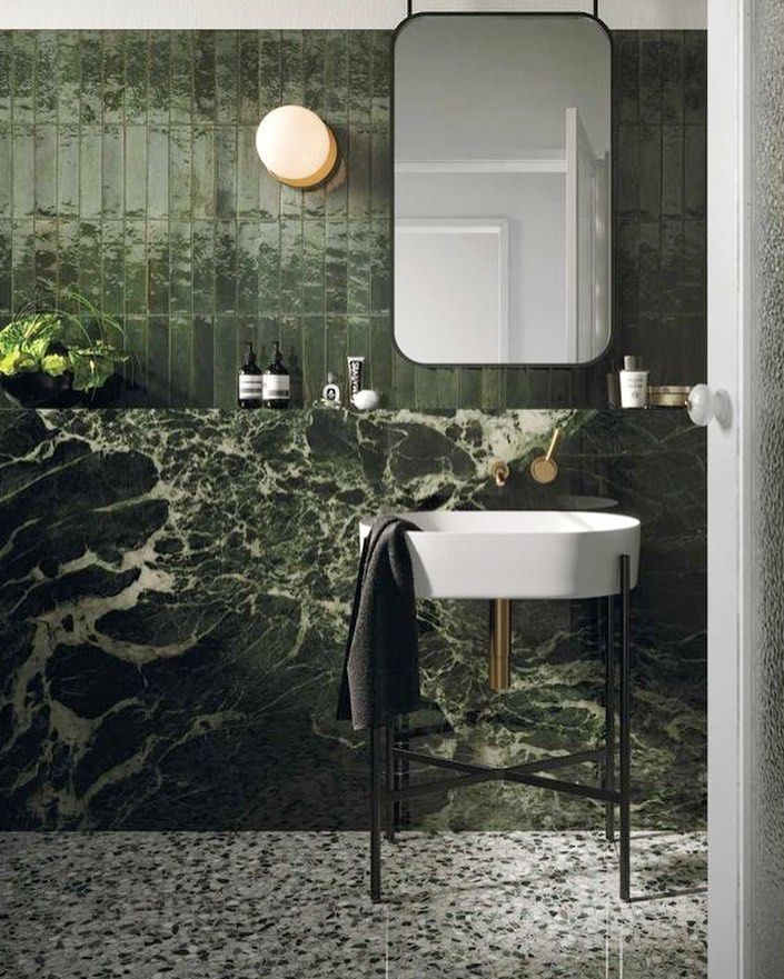 Deep green tiled powder room with terrazzo floor and black framed mirror