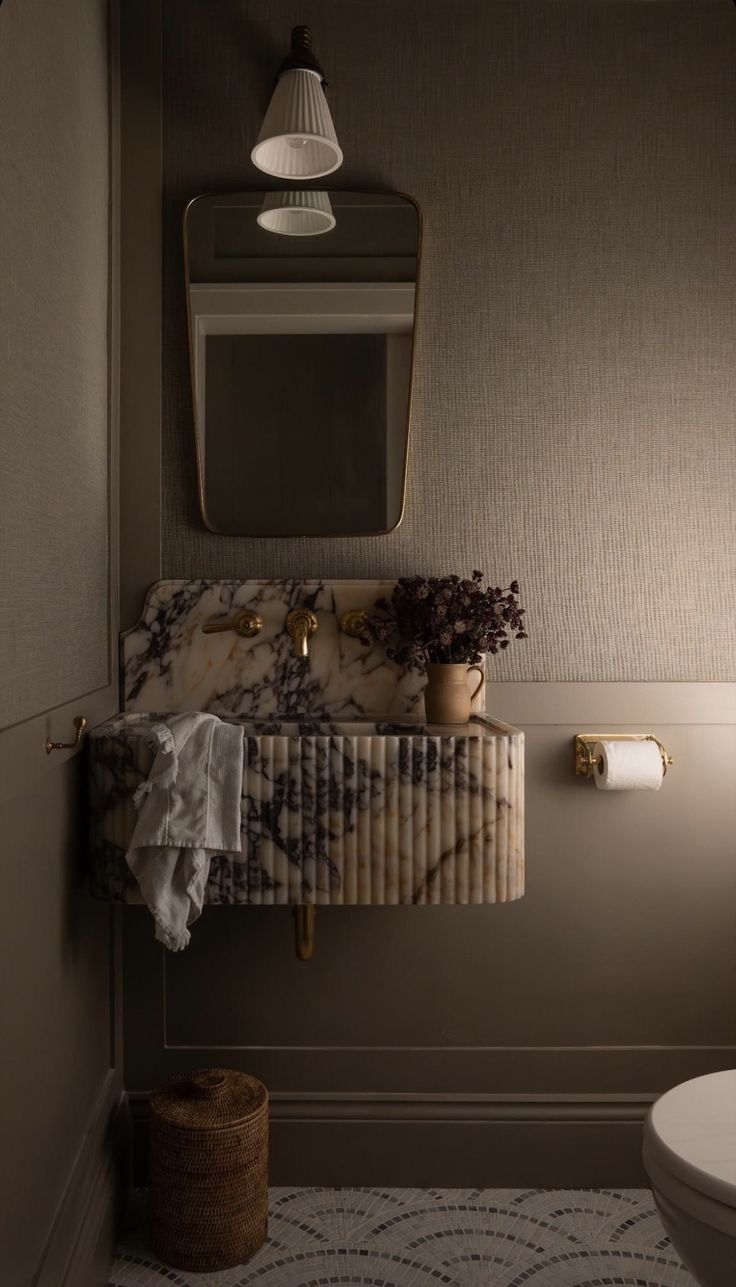 Taupe grasscloth powder room with fluted marble vanity and brass tapware