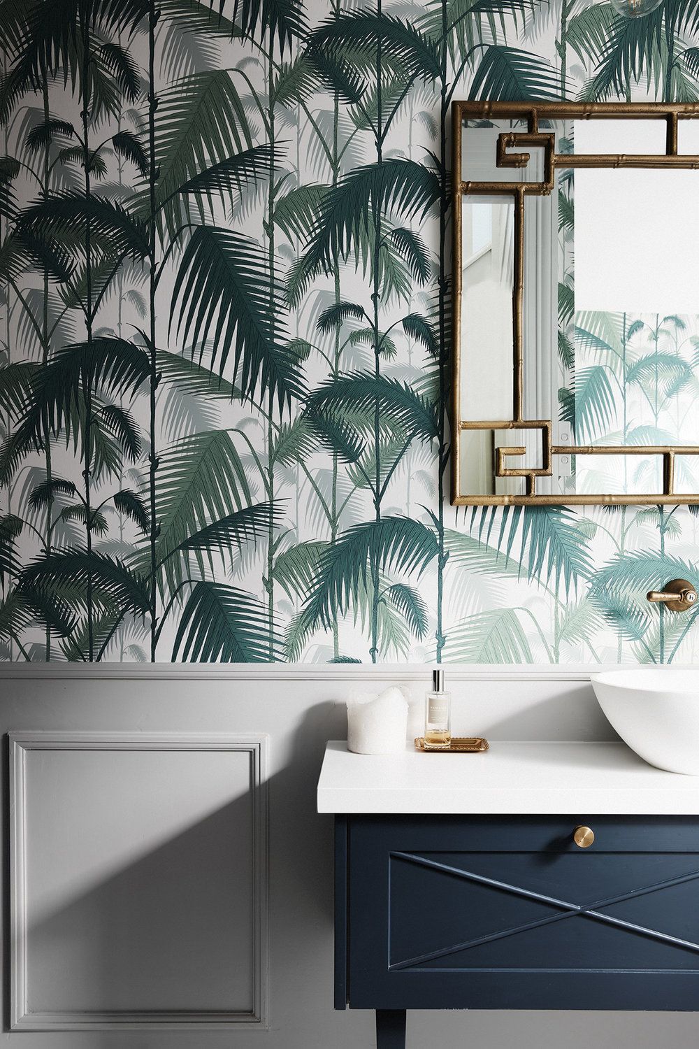 Tropical palm wallpaper powder room with navy vanity and brass mirror