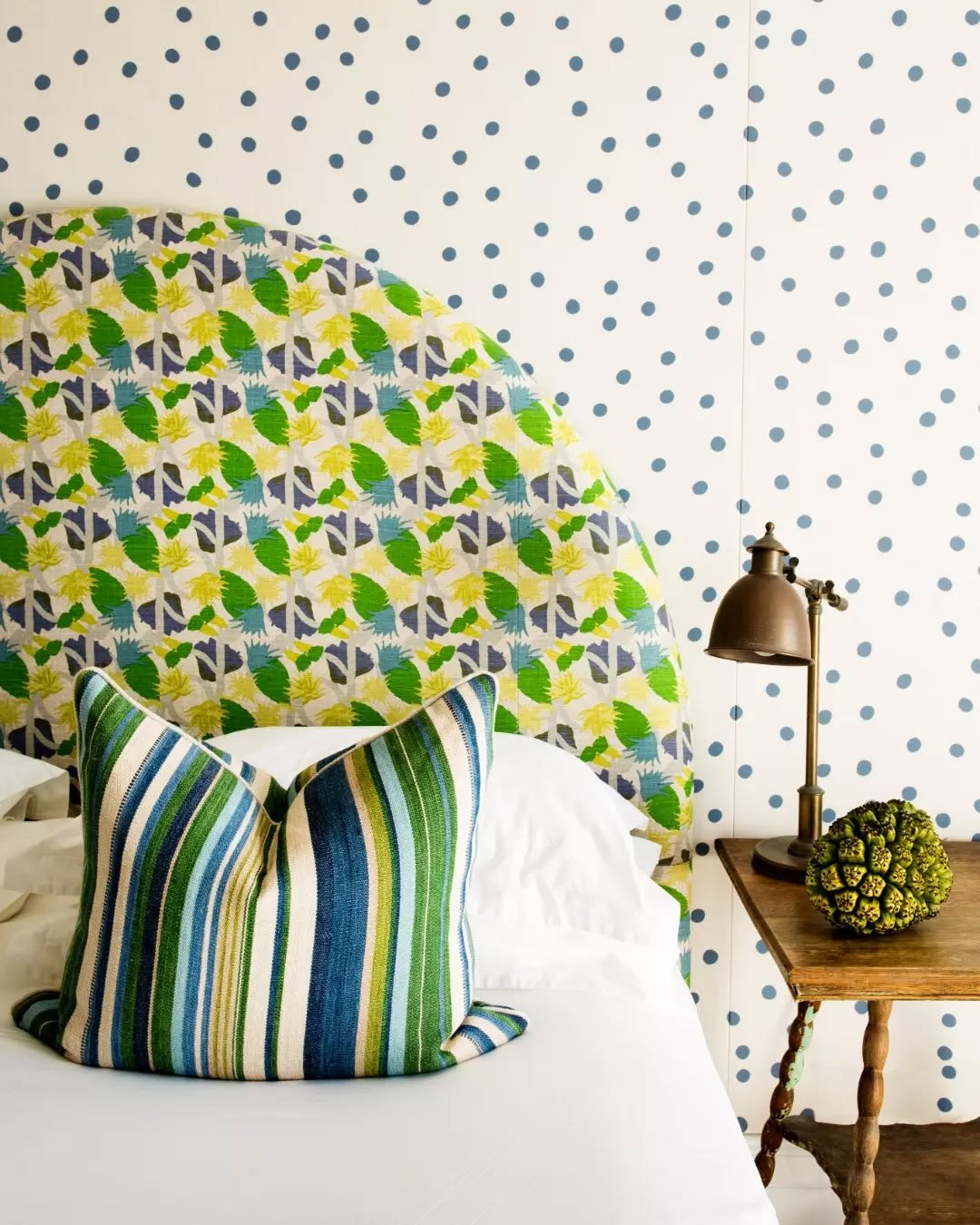 Custom upholstered bedhead in a patterned fabric with a striped cushion
