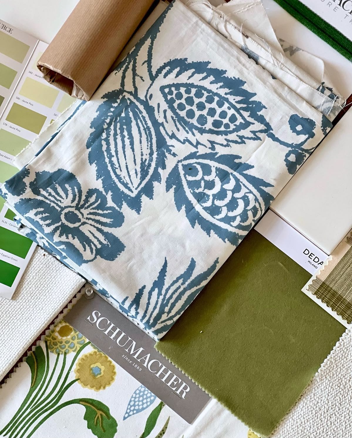 Fabric samples and paint swatches in blue, white and green laid out for selection