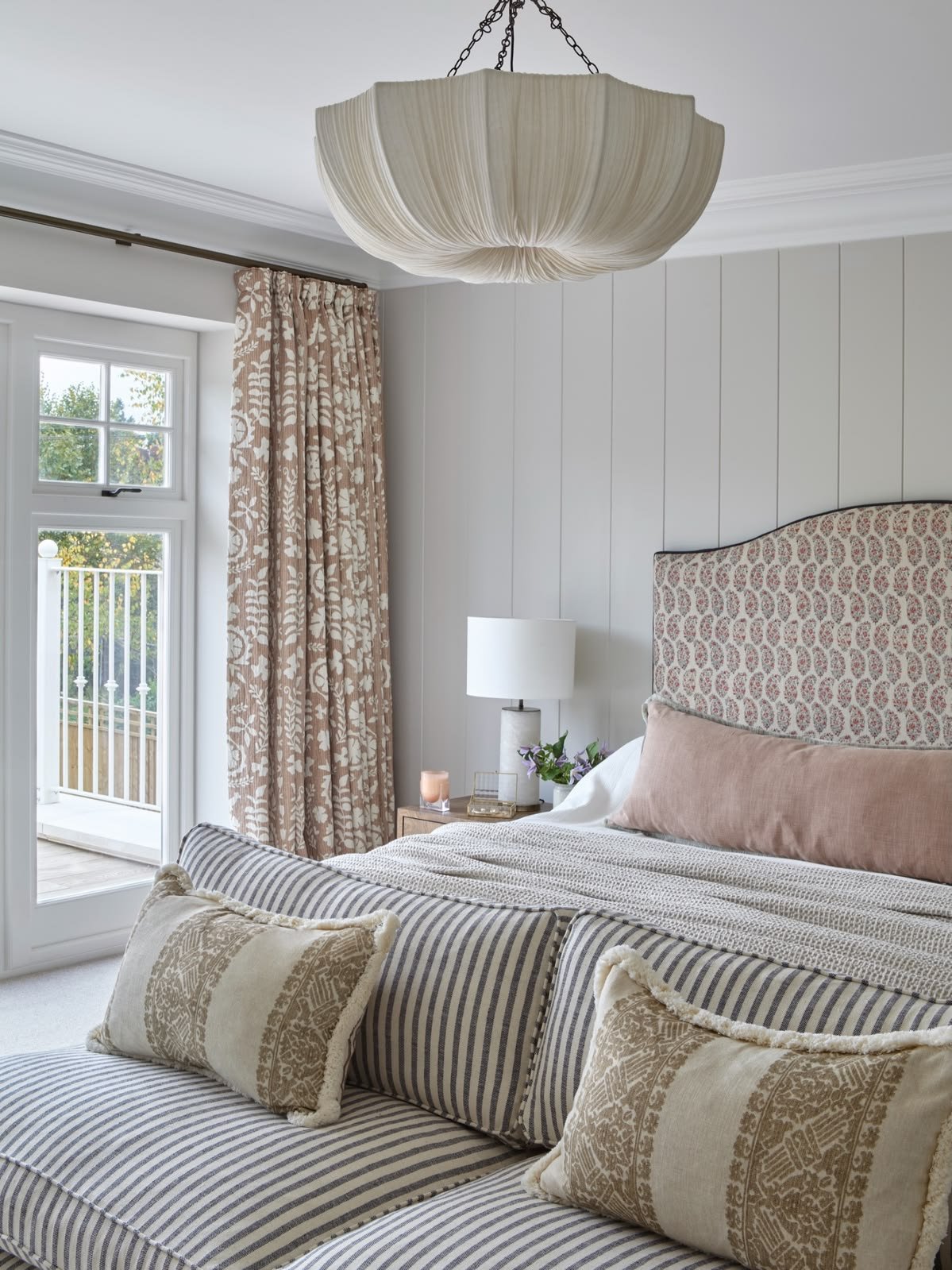 Guest bedroom with upholstered bedhead, striped bedding and layered cushions