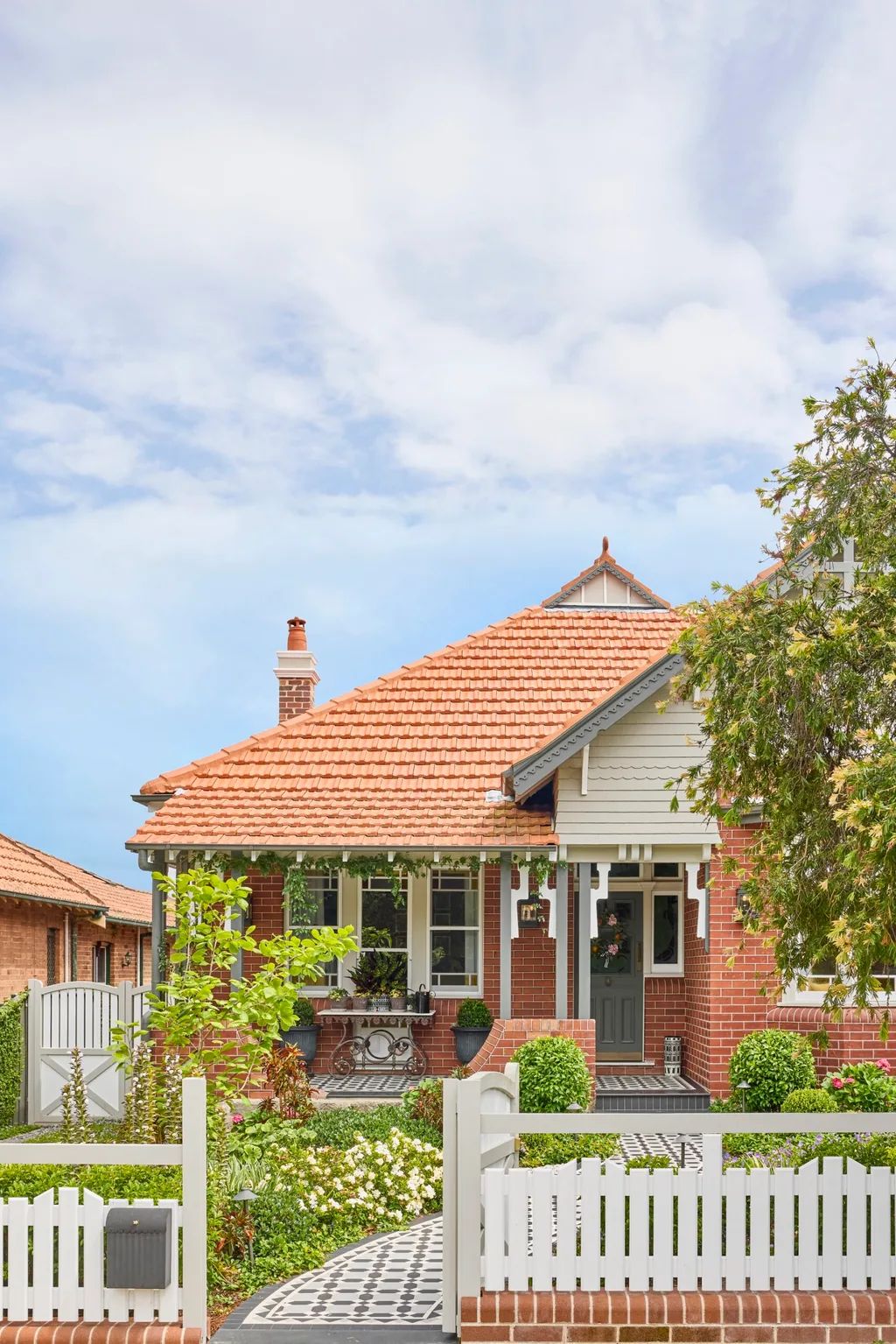 Federation home exterior with terracotta roof tiles, red brick, verandah fretwork and tessellated tile path