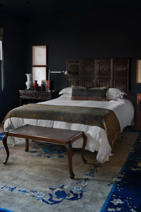 A richly patterned antique rug anchoring a dark, moody bedroom, The Style Workshop