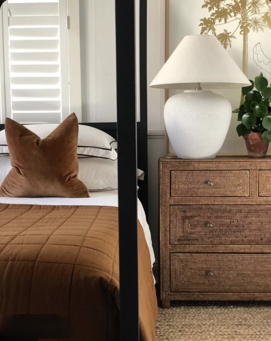 Bedside vignette mixing a rattan chest of drawers, plaster lamp and black metal bed frame, The Style Workshop