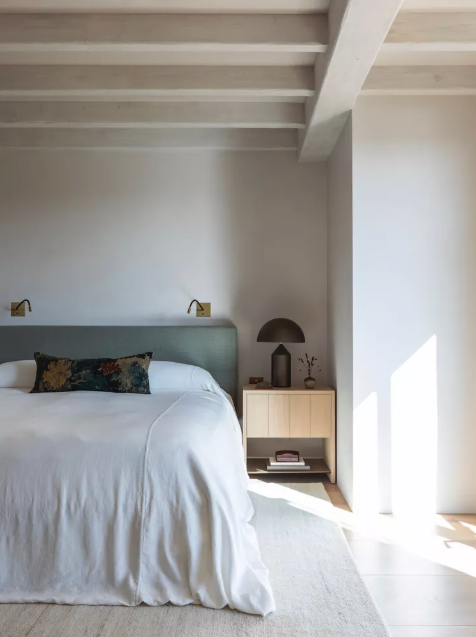 Bed styled with a single patterned lumbar cushion against a plain upholstered headboard, The Style Workshop
